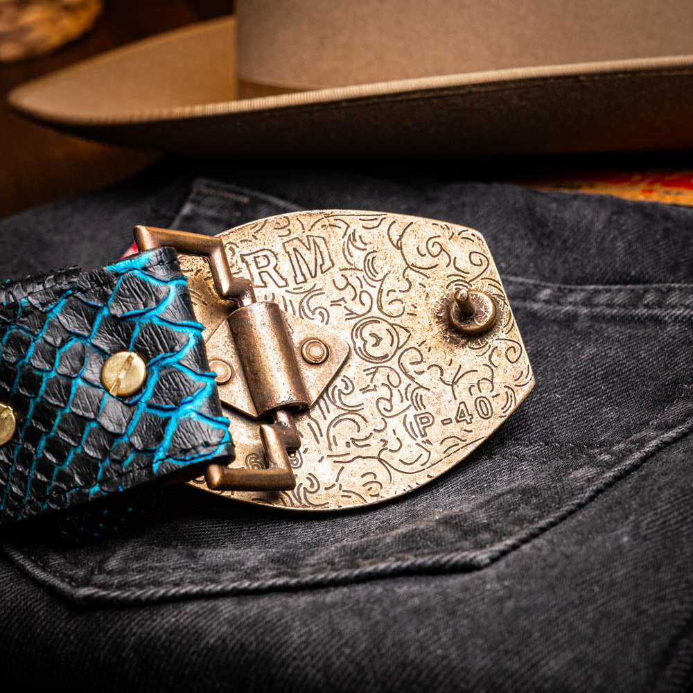 The Arkansas Belt Black / Blue by Marco Di Milano features a handcrafted black snakeskin pattern and a gold and black "MD" buckle, displayed against a white background.