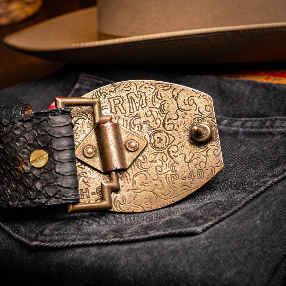 The Arkansas Belt Black by Marco Di Milano features textured black leather and a gold MD monogram buckle, shown coiled on a white background.