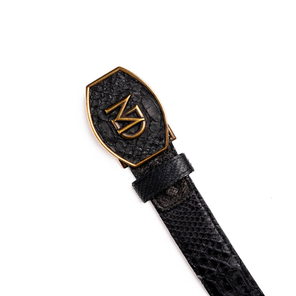 The Arkansas Belt Black by Marco Di Milano features textured black leather and a gold MD monogram buckle, shown coiled on a white background.