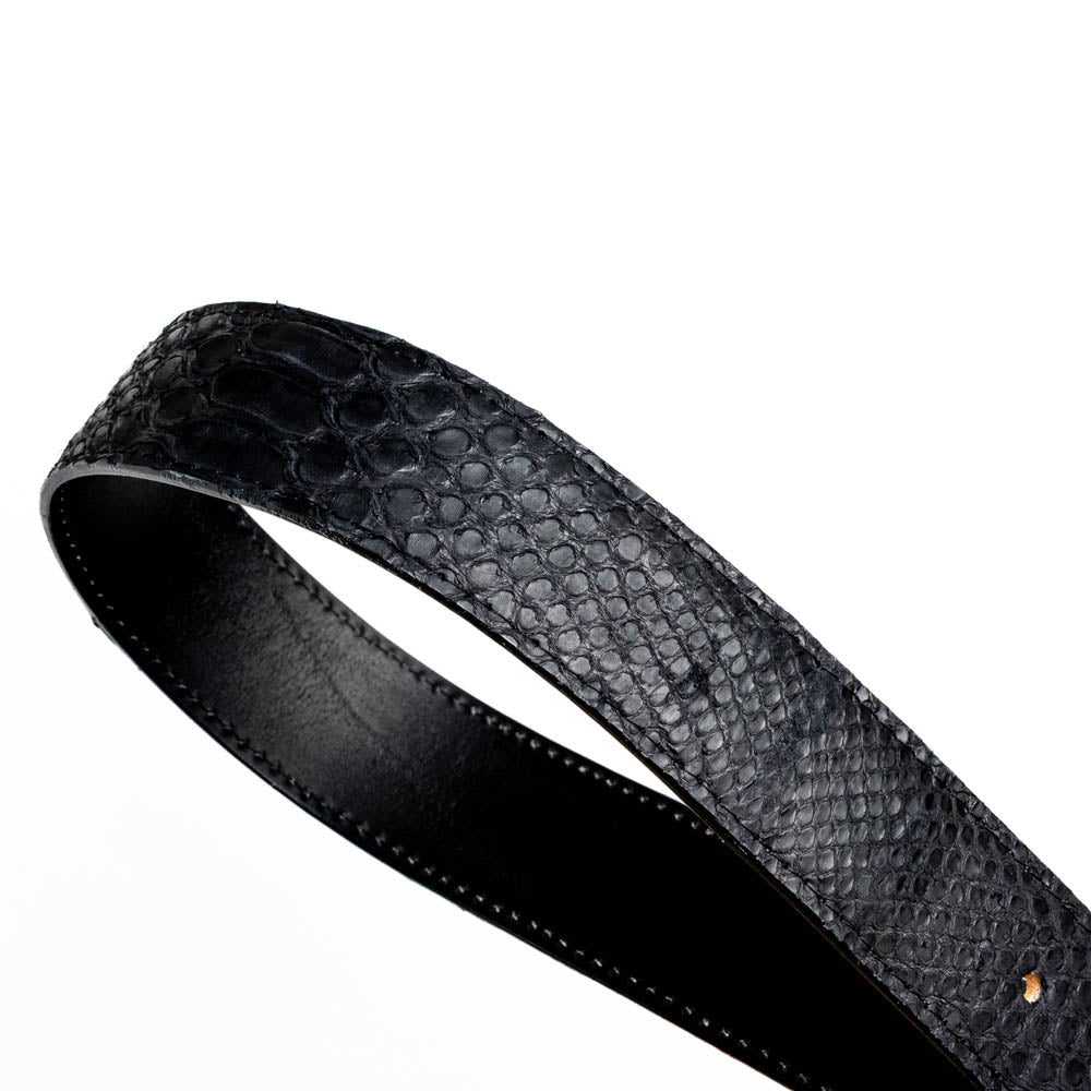 The Arkansas Belt Black by Marco Di Milano features textured black leather and a gold MD monogram buckle, shown coiled on a white background.