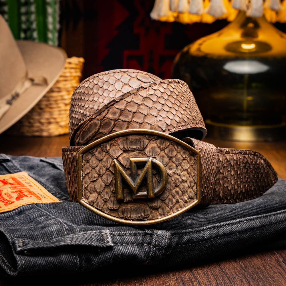 The Arkansas Belt Brown by Marco Di Milano is a handcrafted western accessory in genuine python skin, featuring a gold-tone buckle with overlapping "M" and "D" letters.