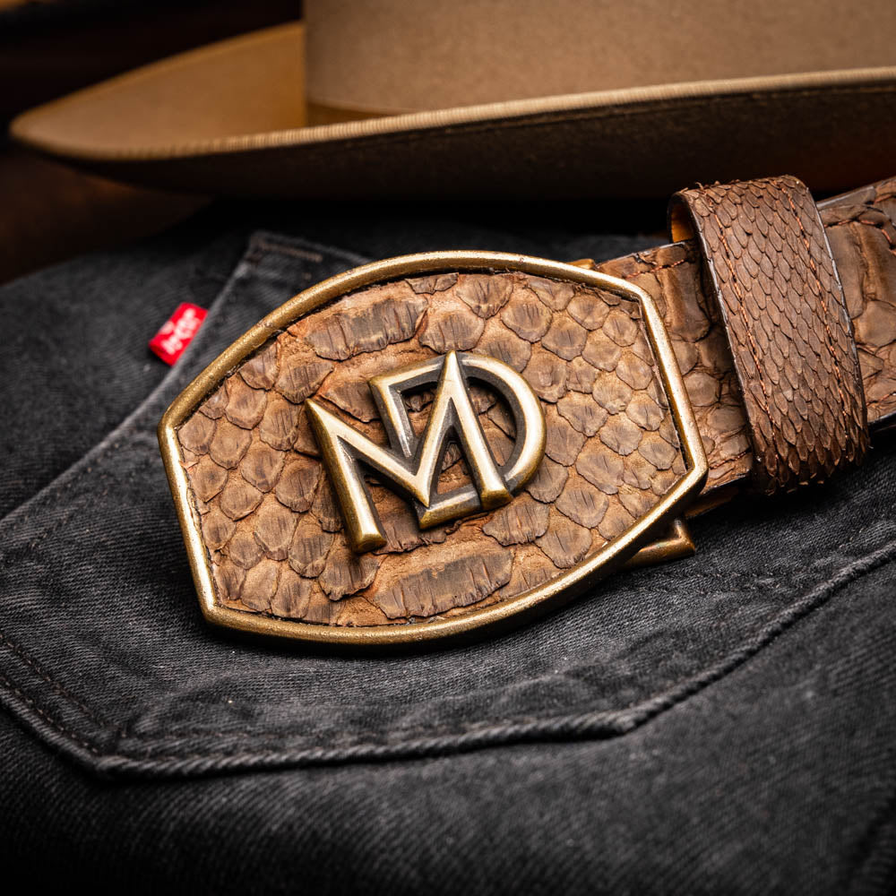 The Arkansas Belt Brown by Marco Di Milano is a handcrafted western accessory in genuine python skin, featuring a gold-tone buckle with overlapping "M" and "D" letters.
