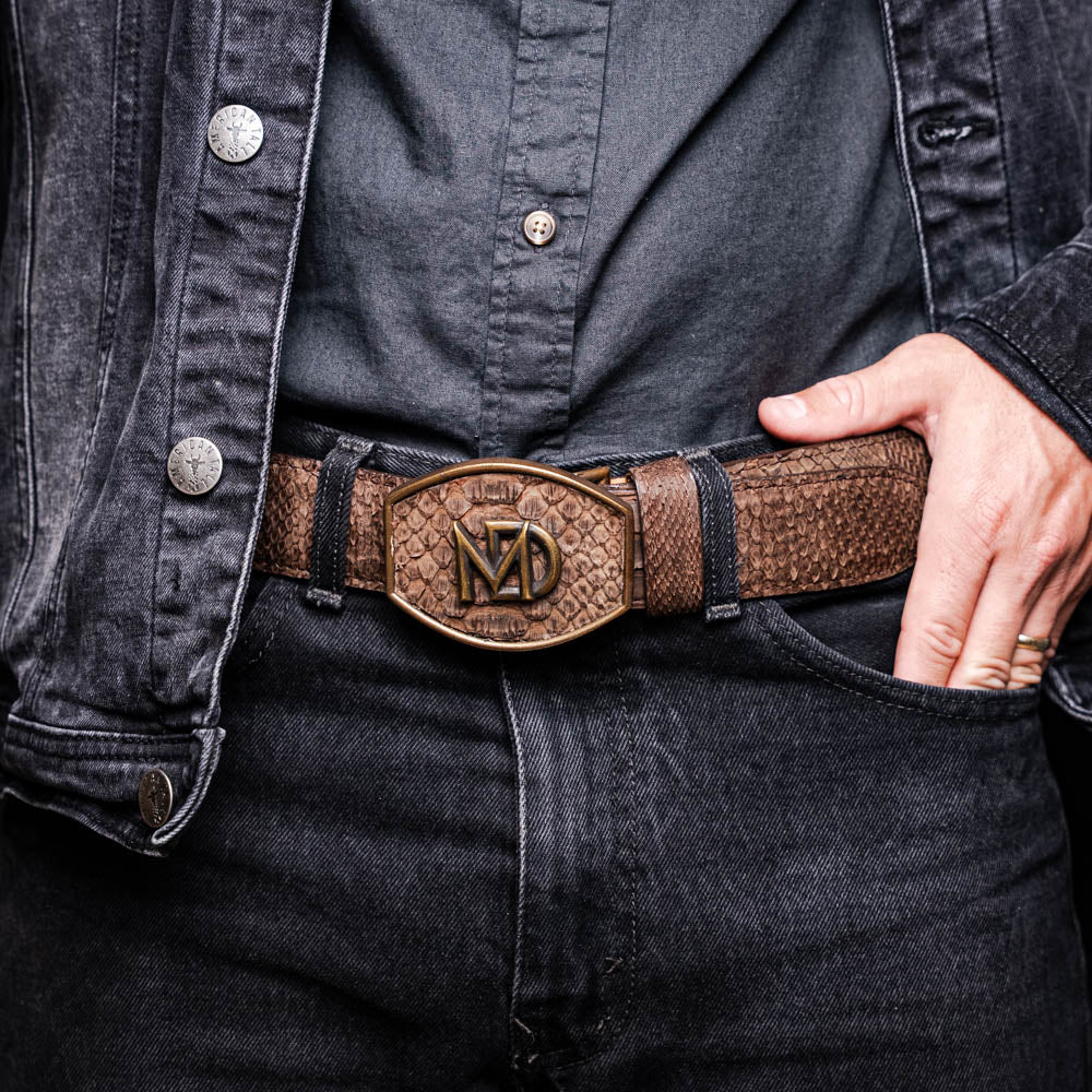 The Arkansas Belt Brown by Marco Di Milano is a handcrafted western accessory in genuine python skin, featuring a gold-tone buckle with overlapping "M" and "D" letters.