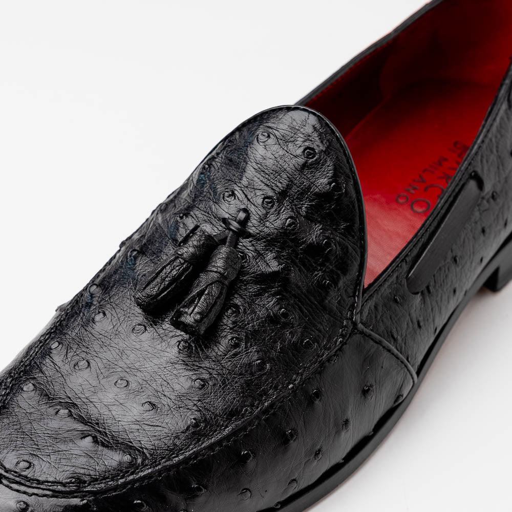 The Aubiere Black by Marco Di Milano are luxury men's tassel loafers in black genuine ostrich leather, shown with one shoe upright and the other displaying a tan sole embossed with the Marco Di Milano logo.