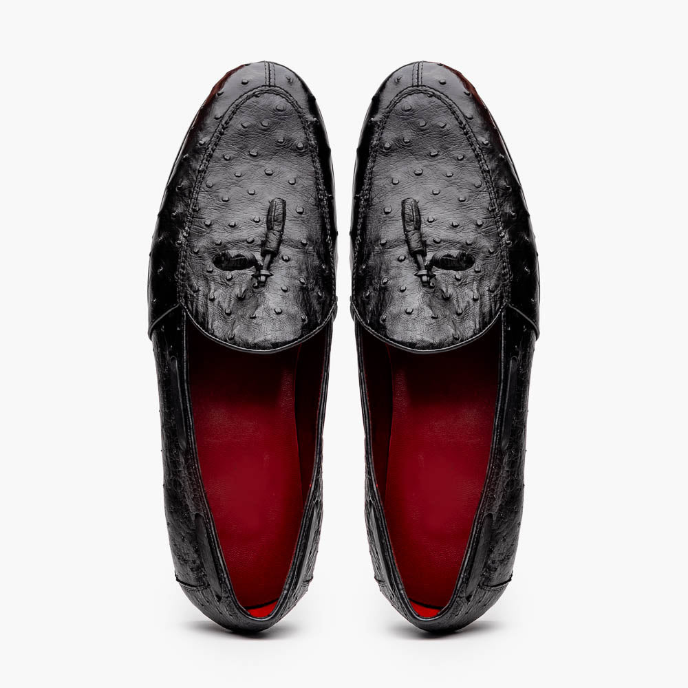 The Aubiere Black by Marco Di Milano are luxury men's tassel loafers in black genuine ostrich leather, shown with one shoe upright and the other displaying a tan sole embossed with the Marco Di Milano logo.