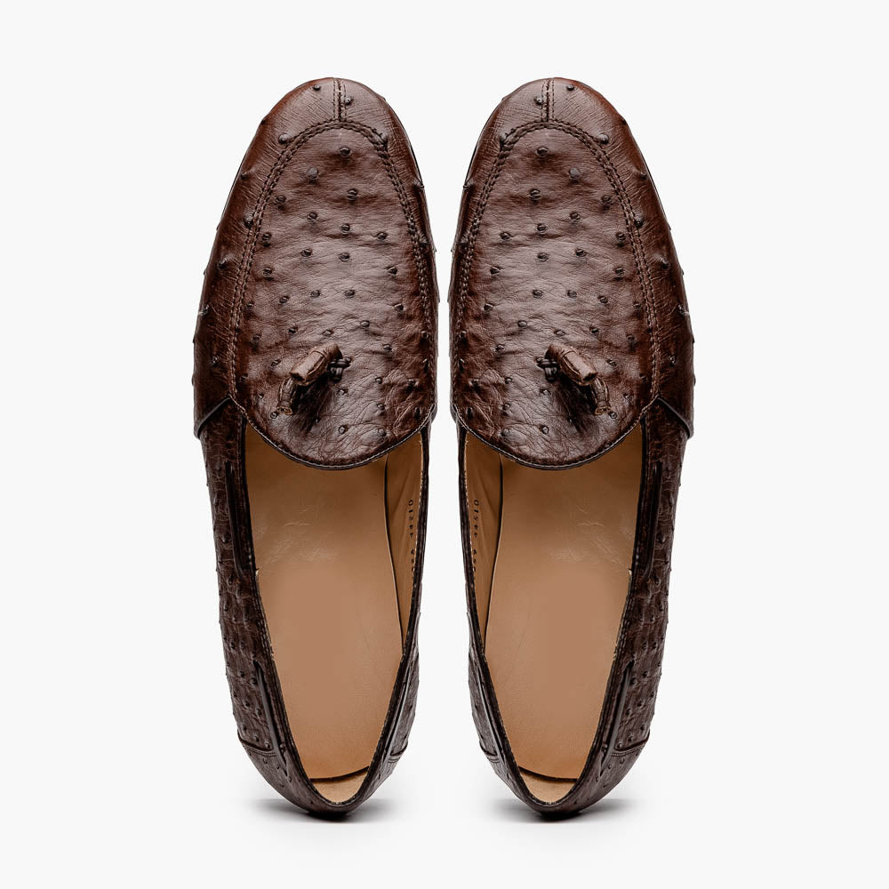 A pair of Marco Di Milano Aubiere Brown men's loafers, featuring brown leather with a textured pattern and tassel detail; one shoe stands upright while the other lies on its side showing the branded sole.