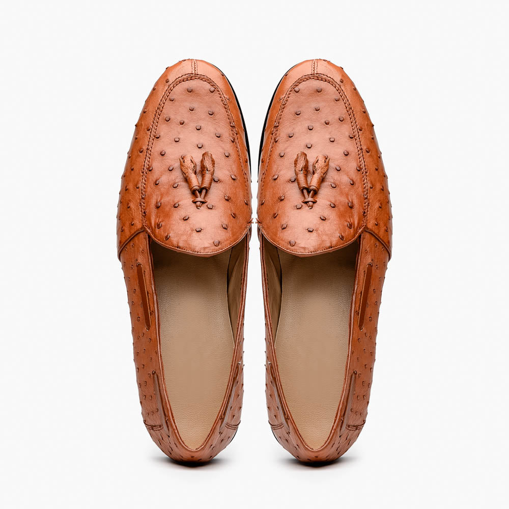 A pair of luxury men's footwear—Aubiere Cognac loafers by Marco Di Milano—boasts rich brown ostrich leather, with one shoe upright and the other on its side to reveal a sole stamped "Marco Di Milano.