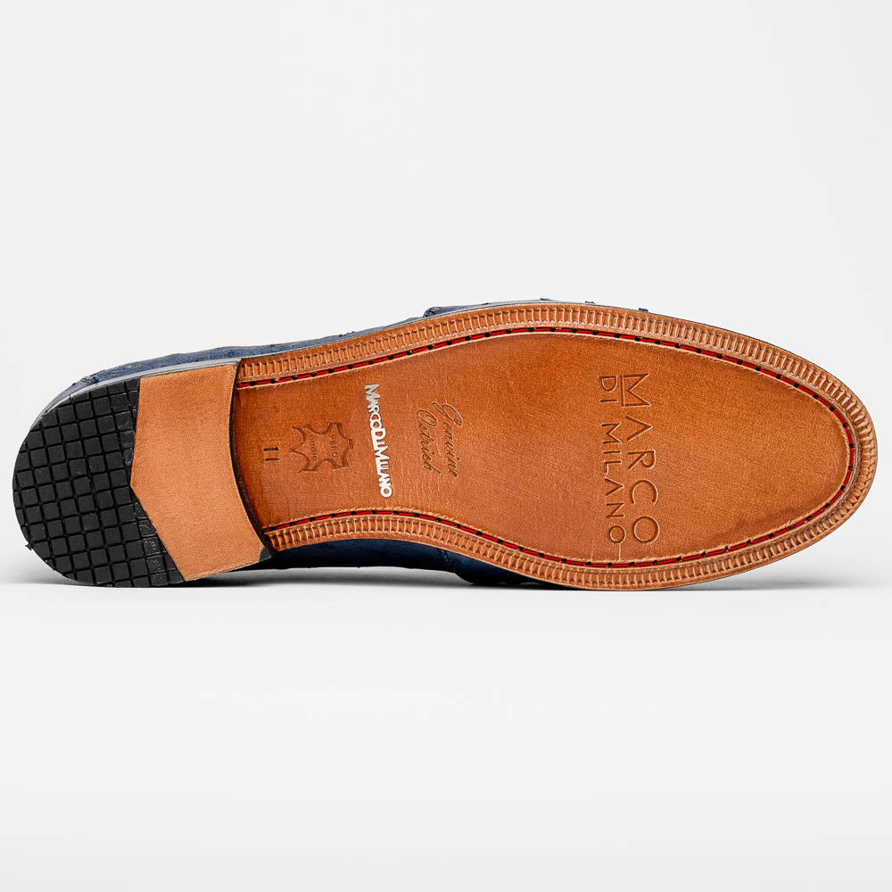 A pair of luxury men's footwear: the Aubiere Navy by Marco Di Milano—blue ostrich tassel loafers with red inner lining and brown leather soles, one shoe propped to display the sole branding.
