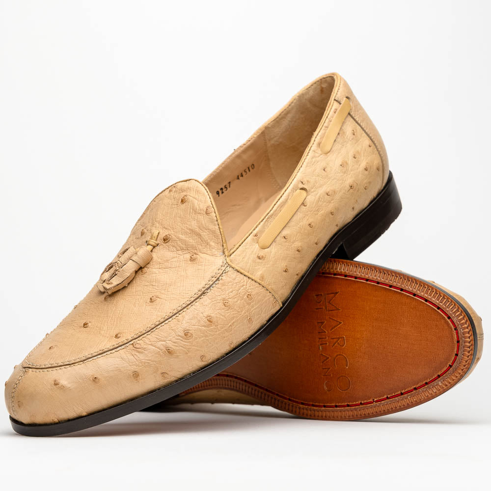 The Aubiere Orix by Marco Di Milano features beige ostrich tassel loafers—one upright, one showing the stitched brown leather sole—ideal for luxury men’s footwear enthusiasts.