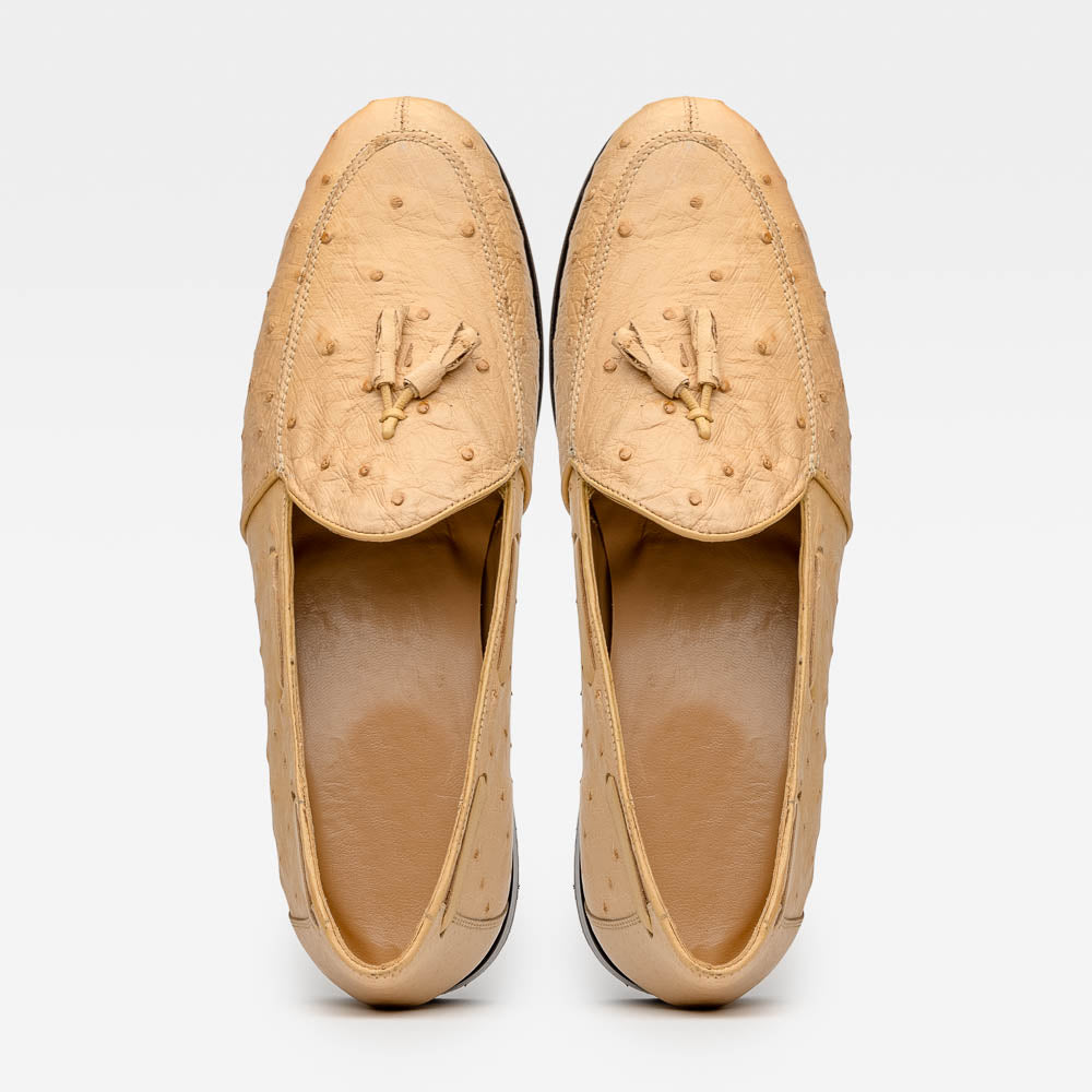 The Aubiere Orix by Marco Di Milano features beige ostrich tassel loafers—one upright, one showing the stitched brown leather sole—ideal for luxury men’s footwear enthusiasts.