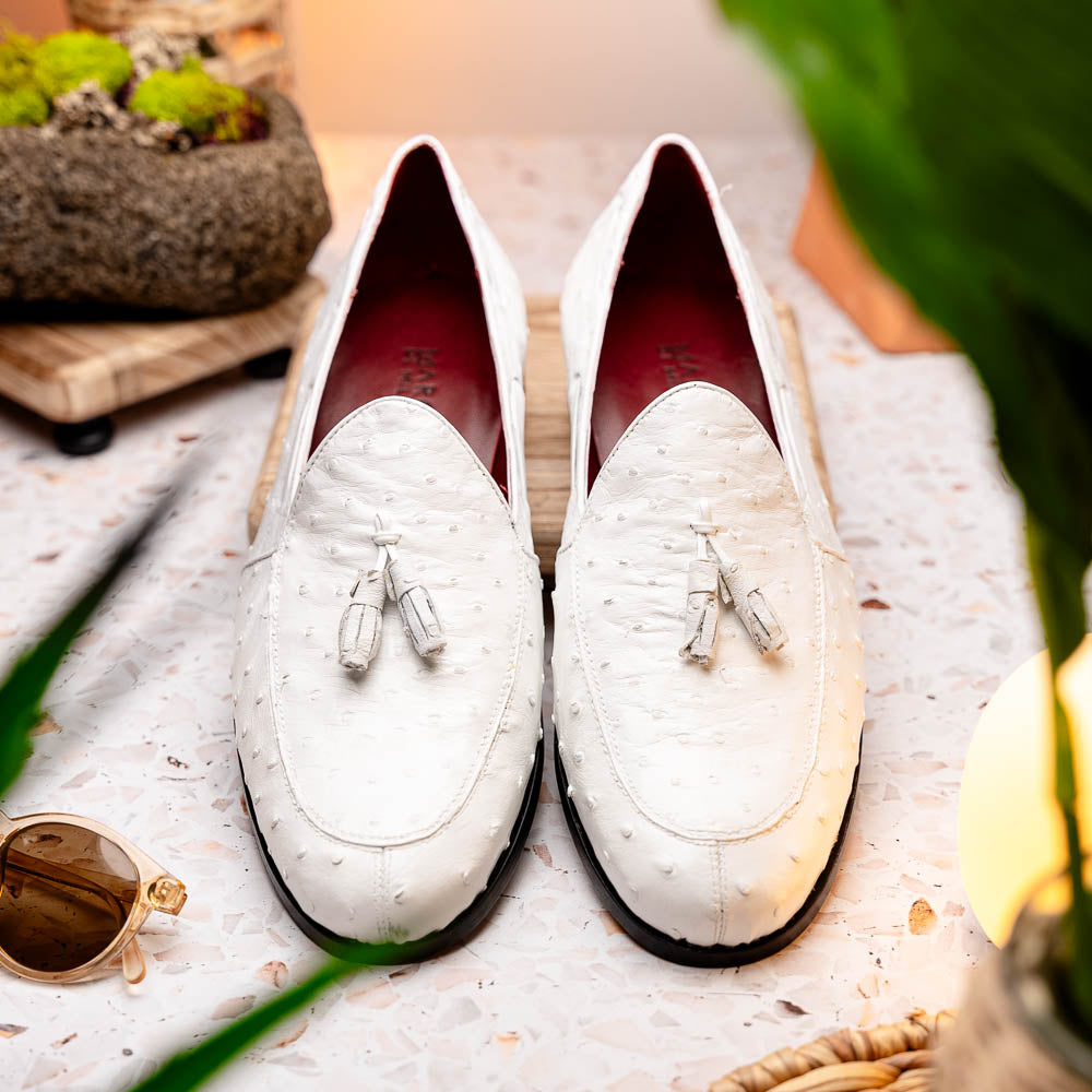 A pair of luxury men’s loafers—Marco Di Milano Aubiere White—crafted in textured white leather with ostrich tassels, red interior lining, tan soles; one shoe rests on its side showing the “Marco Di Milano” logo.