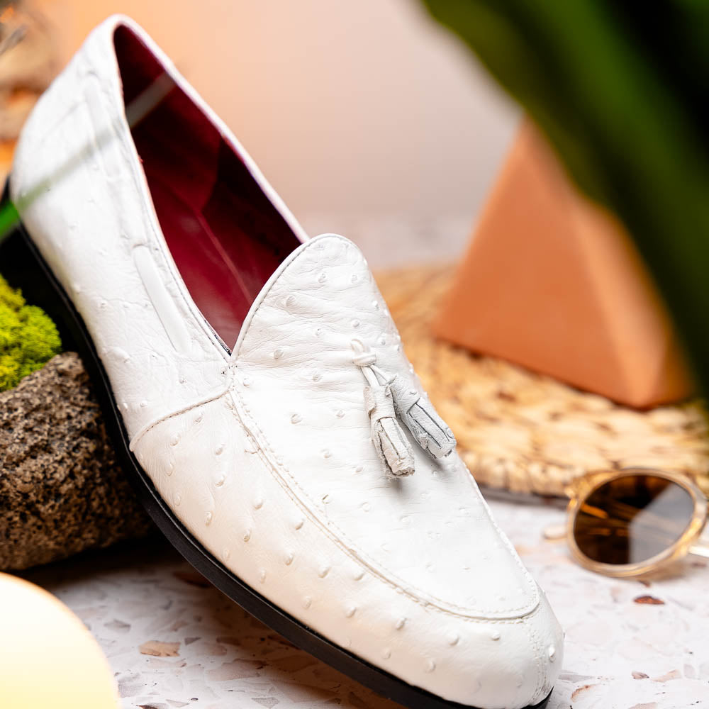 A pair of luxury men’s loafers—Marco Di Milano Aubiere White—crafted in textured white leather with ostrich tassels, red interior lining, tan soles; one shoe rests on its side showing the “Marco Di Milano” logo.