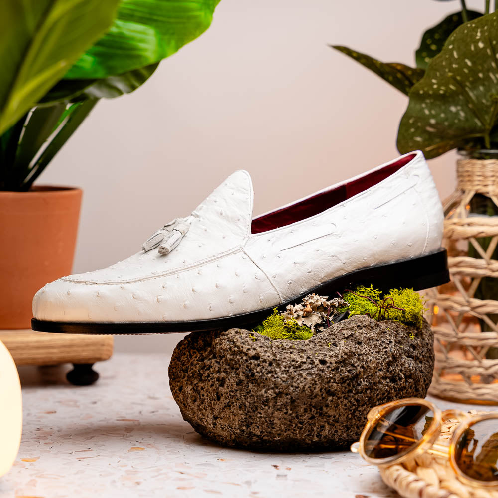 A pair of luxury men’s loafers—Marco Di Milano Aubiere White—crafted in textured white leather with ostrich tassels, red interior lining, tan soles; one shoe rests on its side showing the “Marco Di Milano” logo.