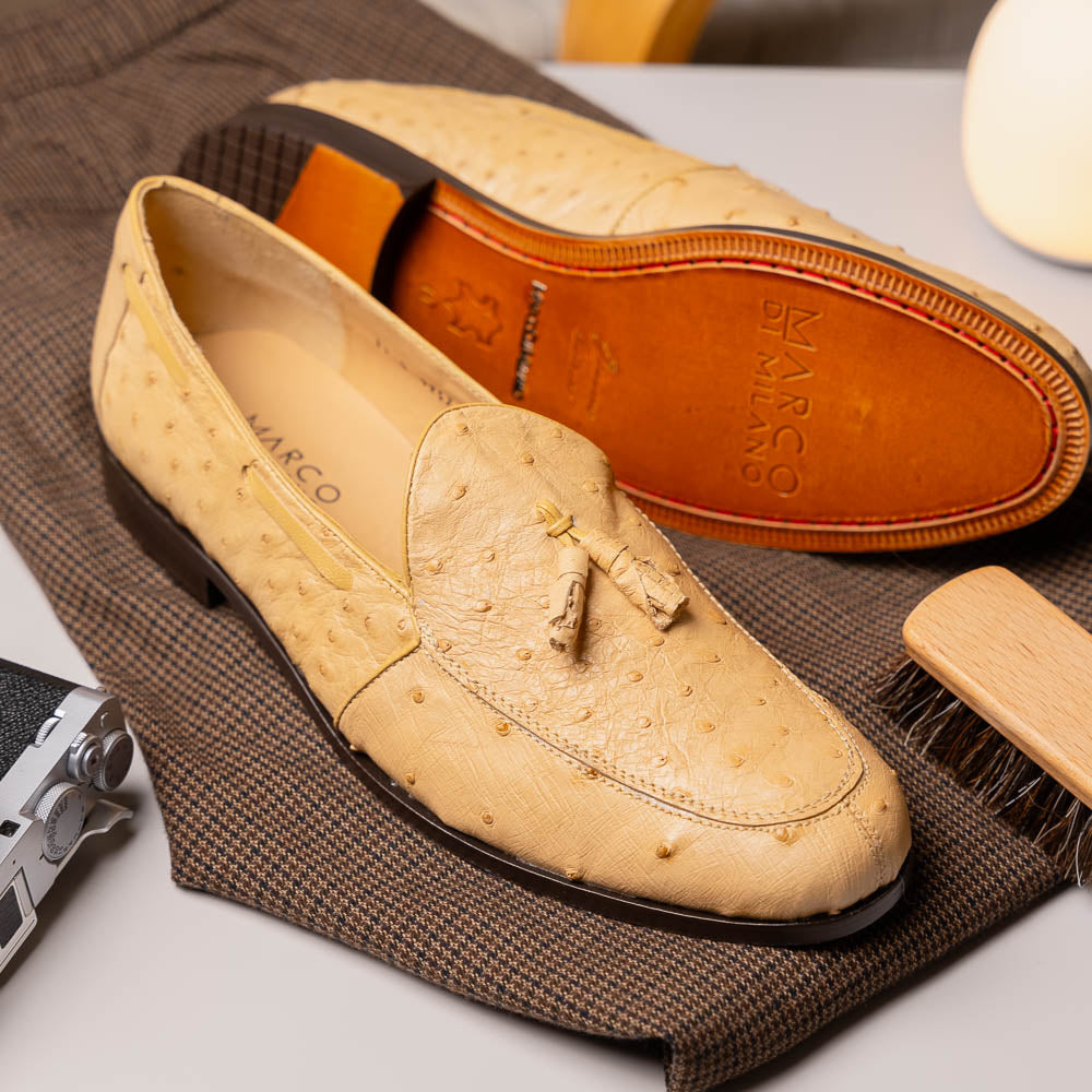 The Aubiere Orix by Marco Di Milano features beige ostrich tassel loafers—one upright, one showing the stitched brown leather sole—ideal for luxury men’s footwear enthusiasts.