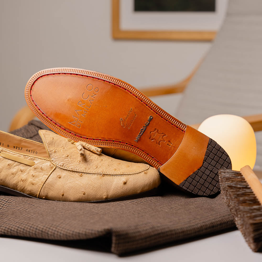 The Aubiere Orix by Marco Di Milano features beige ostrich tassel loafers—one upright, one showing the stitched brown leather sole—ideal for luxury men’s footwear enthusiasts.