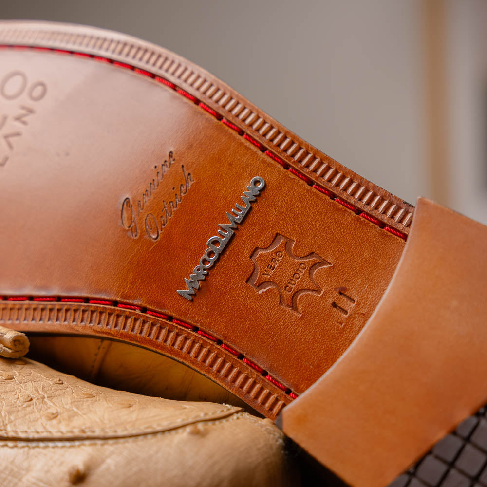 The Aubiere Orix by Marco Di Milano features beige ostrich tassel loafers—one upright, one showing the stitched brown leather sole—ideal for luxury men’s footwear enthusiasts.