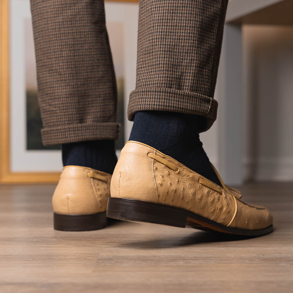 The Aubiere Orix by Marco Di Milano features beige ostrich tassel loafers—one upright, one showing the stitched brown leather sole—ideal for luxury men’s footwear enthusiasts.