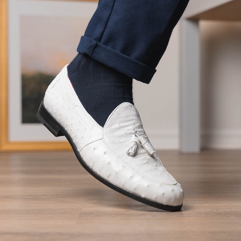 A pair of luxury men’s loafers—Marco Di Milano Aubiere White—crafted in textured white leather with ostrich tassels, red interior lining, tan soles; one shoe rests on its side showing the “Marco Di Milano” logo.