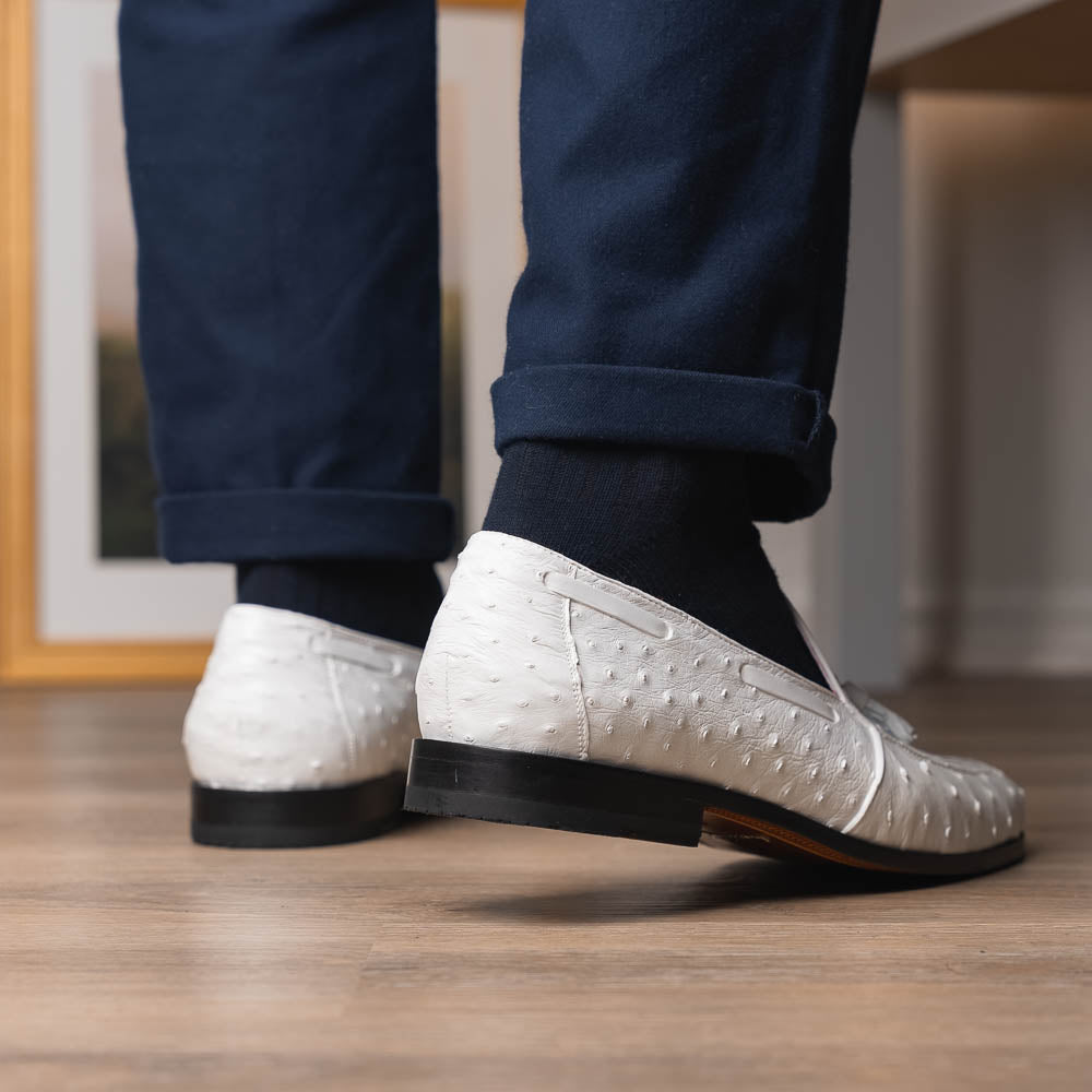 A pair of luxury men’s loafers—Marco Di Milano Aubiere White—crafted in textured white leather with ostrich tassels, red interior lining, tan soles; one shoe rests on its side showing the “Marco Di Milano” logo.