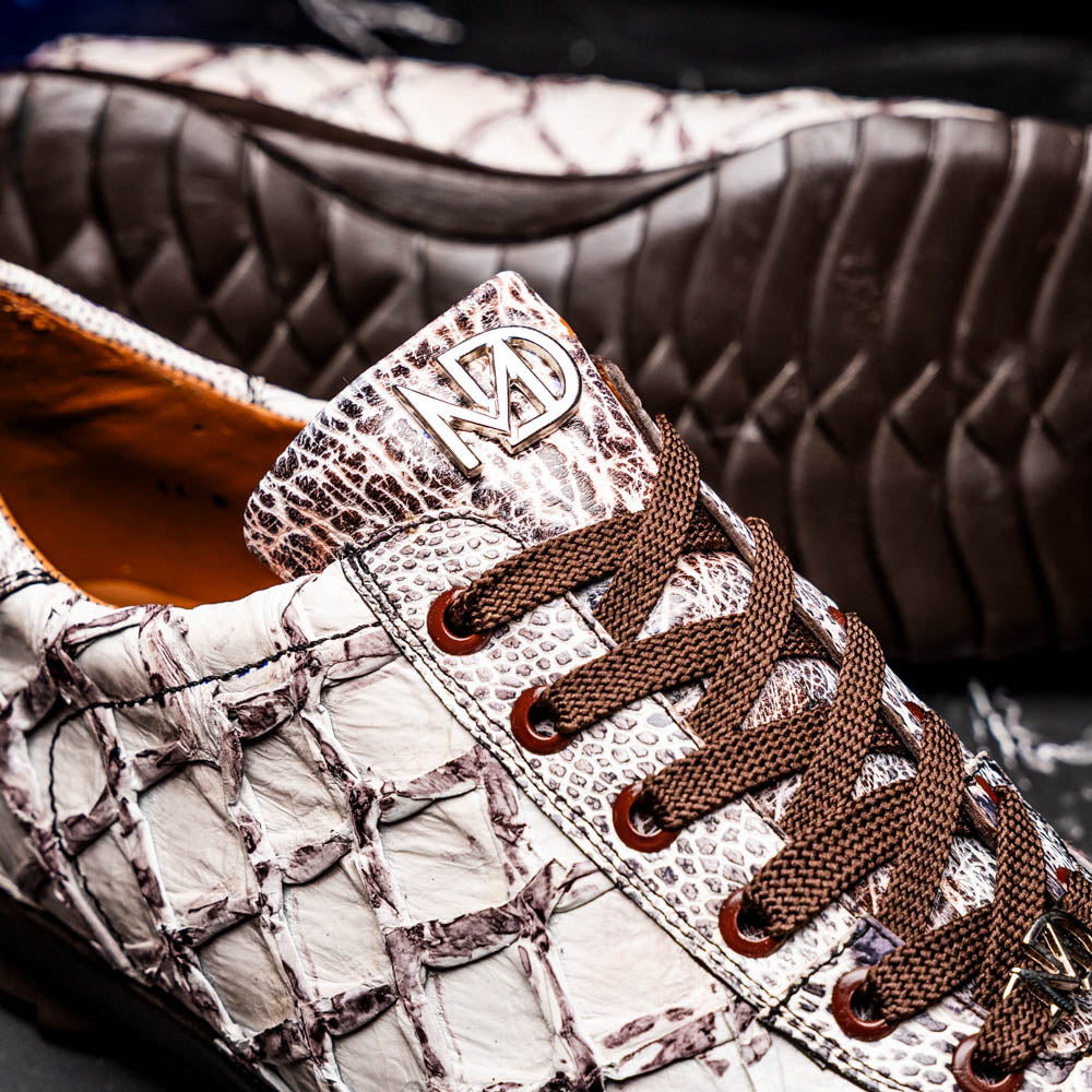 The Marco Di Milano Batistini Newspaper sneakers feature a white and grey crocodile-patterned texture, dark brown laces, and black rubber soles, showcased on a white background.