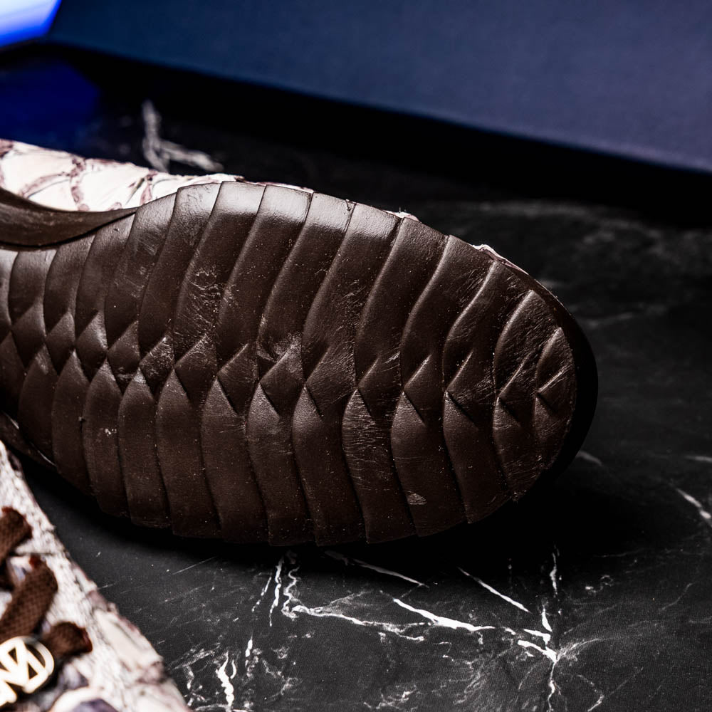 The Marco Di Milano Batistini Newspaper sneakers feature a white and grey crocodile-patterned texture, dark brown laces, and black rubber soles, showcased on a white background.