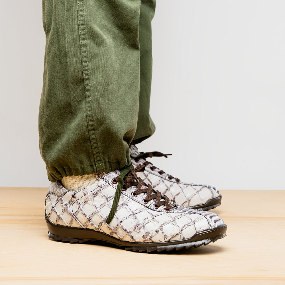 The Marco Di Milano Batistini Newspaper sneakers feature a white and grey crocodile-patterned texture, dark brown laces, and black rubber soles, showcased on a white background.