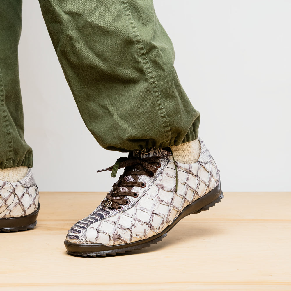 The Marco Di Milano Batistini Newspaper sneakers feature a white and grey crocodile-patterned texture, dark brown laces, and black rubber soles, showcased on a white background.