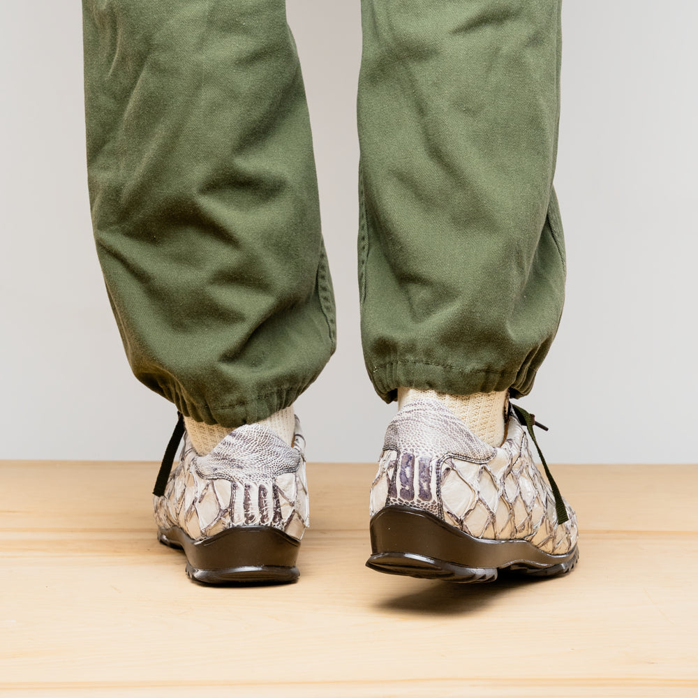 The Marco Di Milano Batistini Newspaper sneakers feature a white and grey crocodile-patterned texture, dark brown laces, and black rubber soles, showcased on a white background.