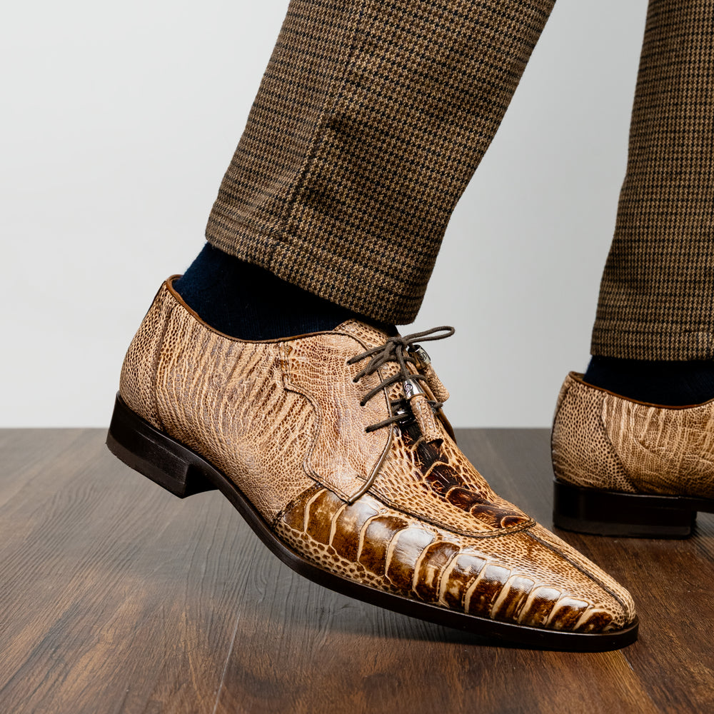 A pair of Belice Rustic Orix handcrafted leather oxford dress shoes by Marco Di Milano, fashioned from tan and brown crocodile leather—one shoe stands upright while the other lies on its side, displaying the sole.