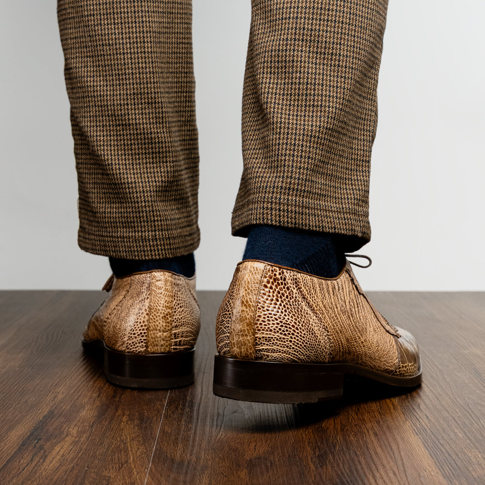 A pair of Belice Rustic Orix handcrafted leather oxford dress shoes by Marco Di Milano, fashioned from tan and brown crocodile leather—one shoe stands upright while the other lies on its side, displaying the sole.