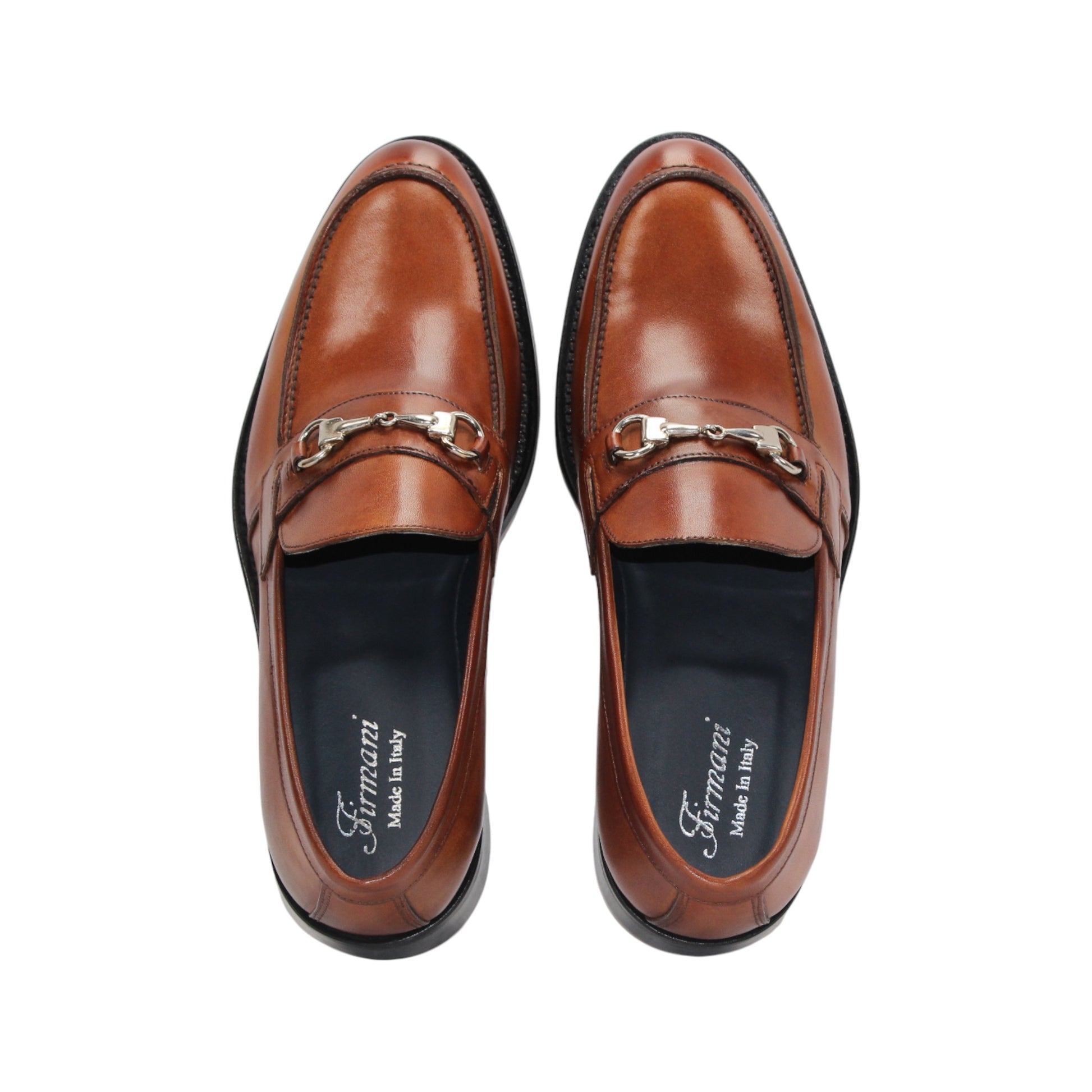 The Firmani Ben Cognac loafer by Firmani features genuine brown leather, a low black heel, and metal bit detail—ideal as a modern dress shoe for any occasion. Displayed on a white background.