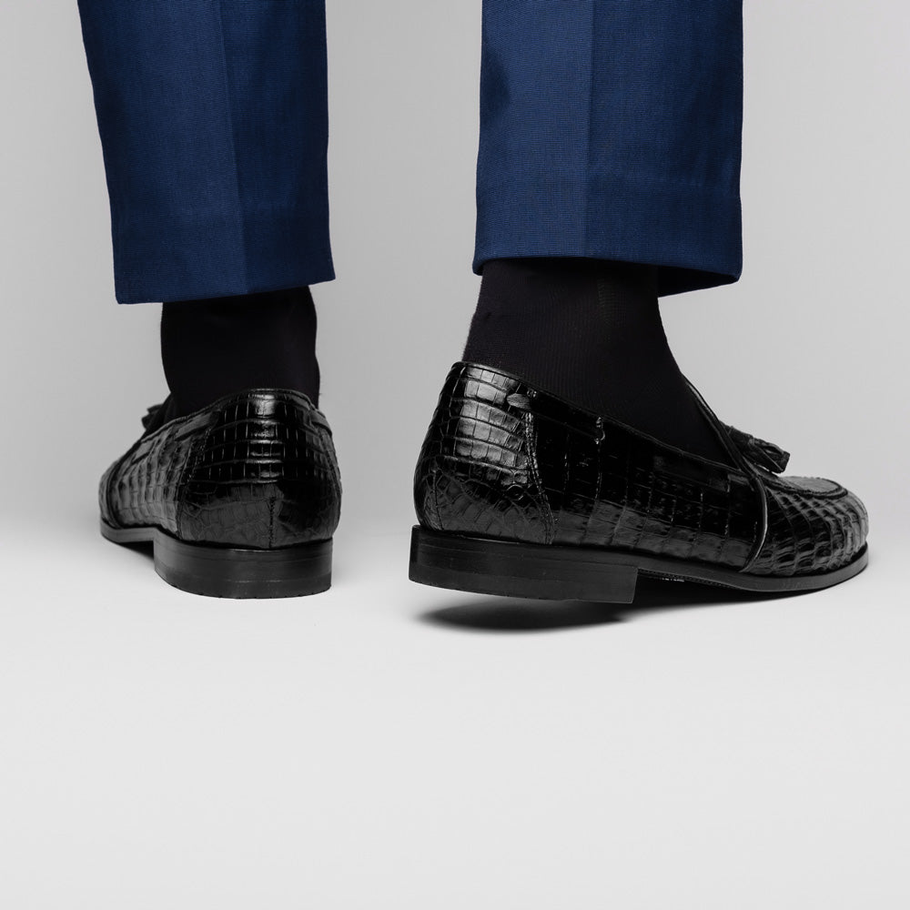 Experience luxury with the Marco Di Milano Bianchi Black—a pair of genuine caiman crocodile tassel loafers featuring black crocodile-patterned leather, red interior lining, and tan leather soles.