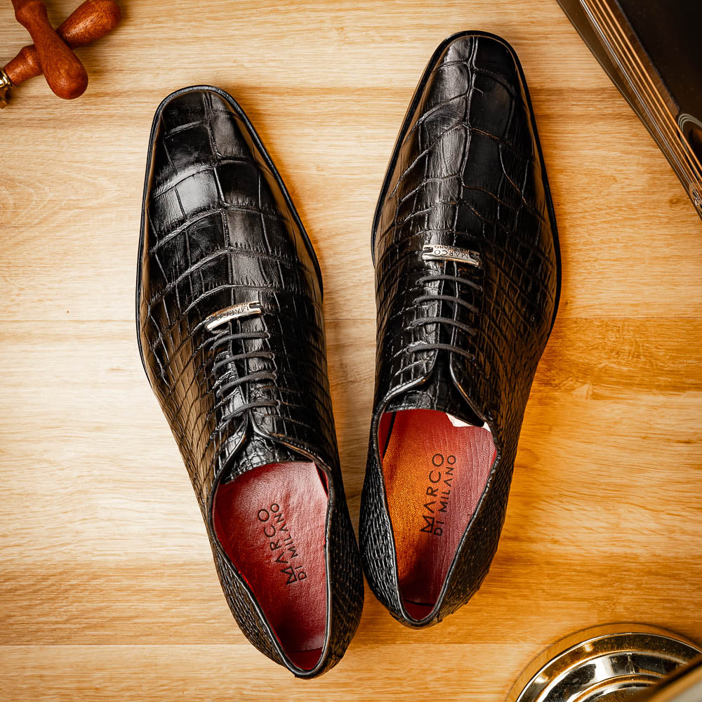 The Marco Di Milano Bono Black features a pair of luxury dress shoes in a crocodile pattern—one upright and one displaying a brown branded sole.