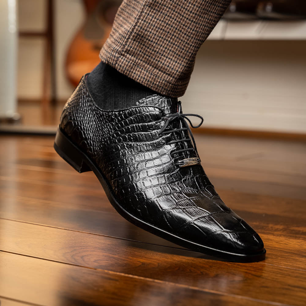 The Marco Di Milano Bono Black features a pair of luxury dress shoes in a crocodile pattern—one upright and one displaying a brown branded sole.