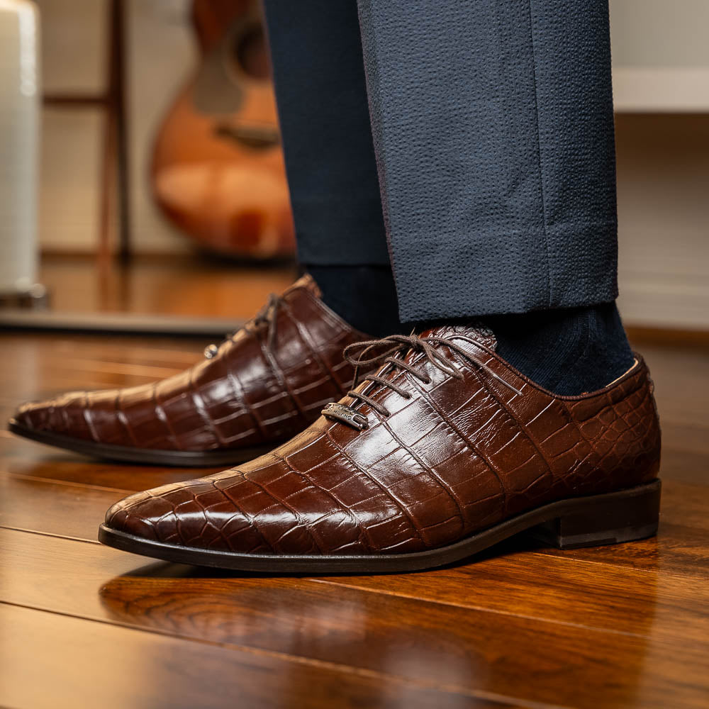The Bono Brown by Marco Di Milano: genuine alligator Oxfords in brown—one upright displaying laces, the other showing the sole and stitching—a stunning example of luxury footwear.