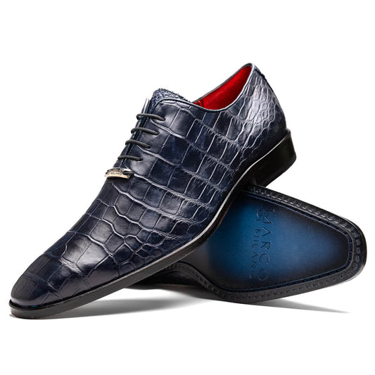 The Bono Navy by Marco Di Milano: luxury navy blue dress shoes with crocodile-patterned leather, black soles, and red inner lining. One shoe is positioned to showcase the sole.