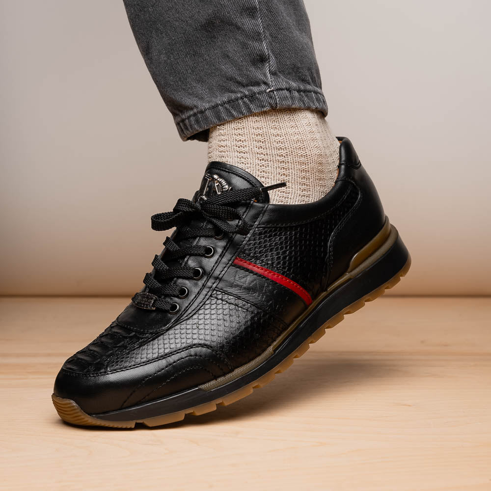 The Marco Di Milano Brescia Black sneakers feature textured black leather, black laces, a red side stripe, and brown rubber soles—one shoe stands upright while the other lies on its side.
