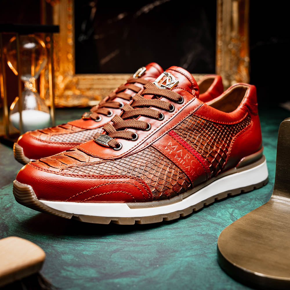 The Marco Di Milano Brescia Antique Cognac sneakers feature brown textured leather, a patterned design, lace-up fronts, white midsoles, and tan rubber outsoles. One shoe is propped against the other.