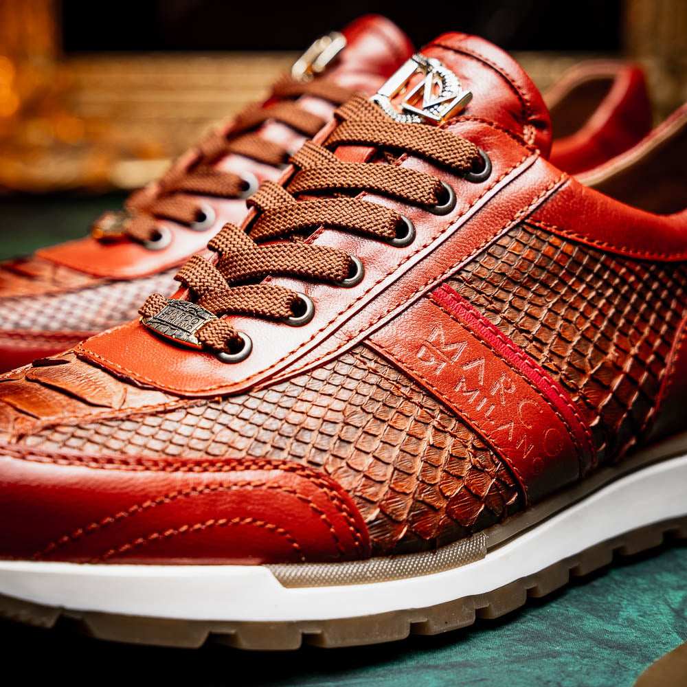 The Marco Di Milano Brescia Antique Cognac sneakers feature brown textured leather, a patterned design, lace-up fronts, white midsoles, and tan rubber outsoles. One shoe is propped against the other.
