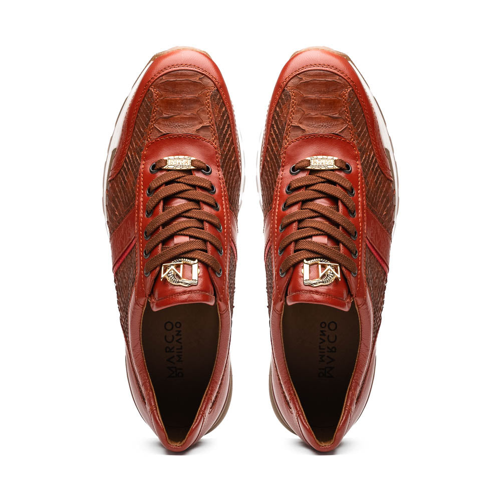 The Marco Di Milano Brescia Antique Cognac sneakers feature brown textured leather, a patterned design, lace-up fronts, white midsoles, and tan rubber outsoles. One shoe is propped against the other.