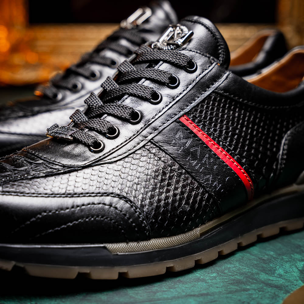 The Marco Di Milano Brescia Black sneakers feature textured black leather, black laces, a red side stripe, and brown rubber soles—one shoe stands upright while the other lies on its side.