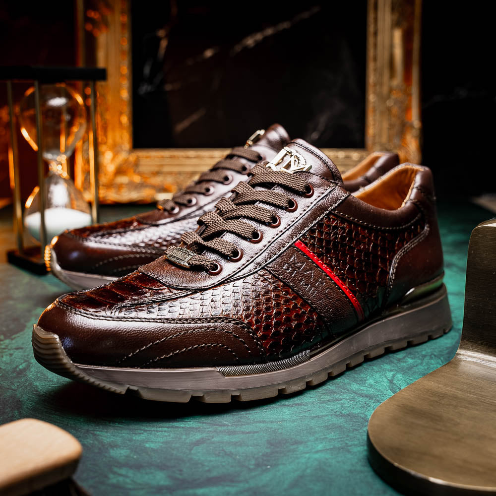 The Marco Di Milano Brescia Brown sneakers feature dark brown python-textured leather, a gold logo on the tongue, and a red stripe detail, with one shoe propped on the other—ideal for luxury footwear enthusiasts.