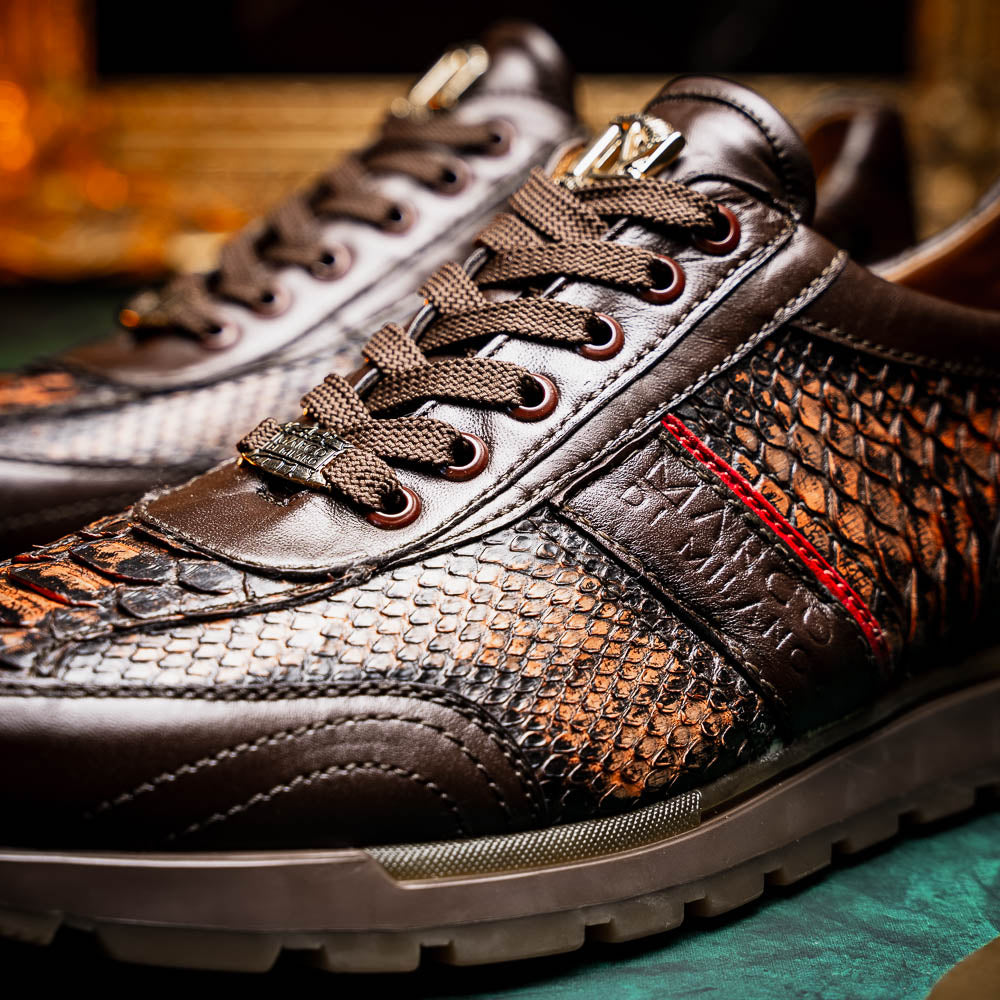 The Marco Di Milano Brescia Washed Cognac sneakers feature brown leather with a snakeskin pattern, gold accents, and rubber soles; one shoe is propped stylishly against the other, showcasing luxury footwear appeal.