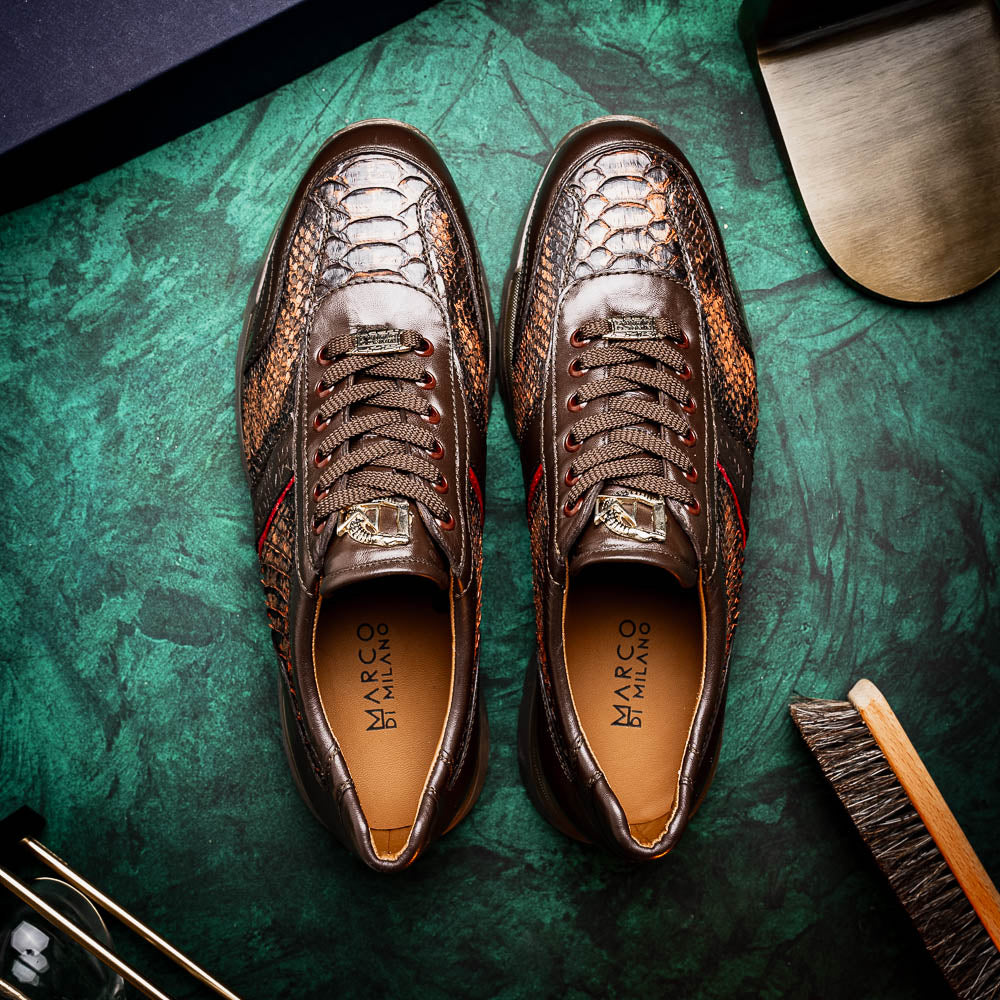 The Marco Di Milano Brescia Washed Cognac sneakers feature brown leather with a snakeskin pattern, gold accents, and rubber soles; one shoe is propped stylishly against the other, showcasing luxury footwear appeal.