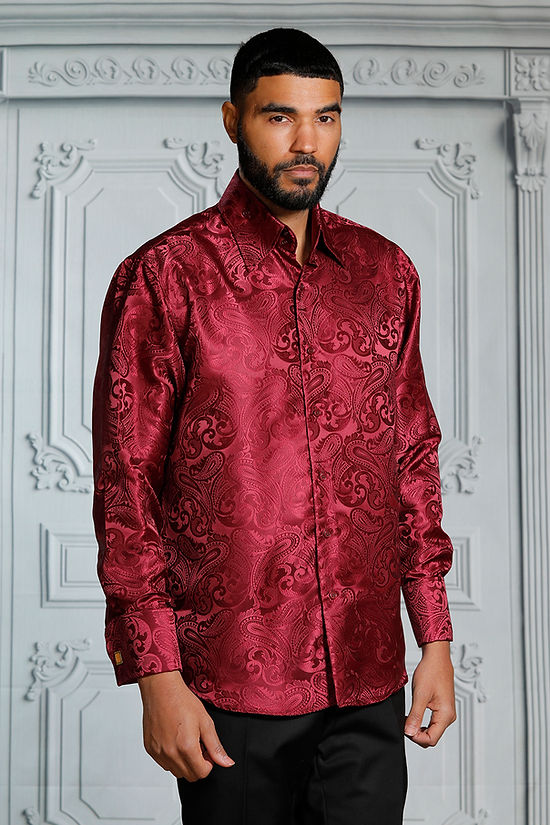 A man stands before an ornate white wall wearing the Manzini MZT-100 Paisley Long Sleeve Satin Burgundy Shirt with links by Manzini.