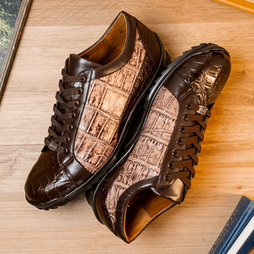 The Marco Di Milano Cairo Brown/Orix men's sneakers feature brown luxury footwear with textured panels and rubber soles, crafted to resemble genuine alligator. One shoe stands upright while the other lies on its side.