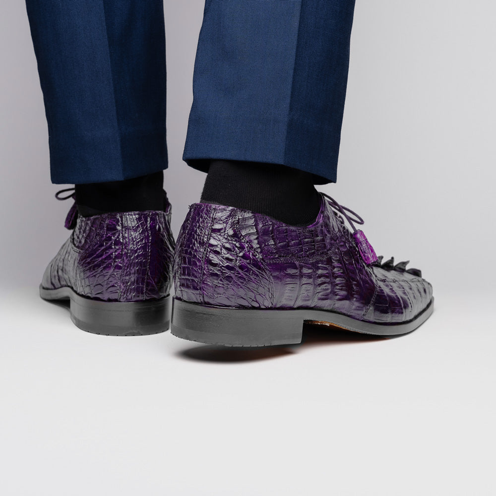 The Marco Di Milano Cancun Purple is a luxurious pair of derby shoes crafted from genuine hornback caiman crocodile leather, hand-painted in purple with black laces—one shown upright, the other displaying a tan branded sole.