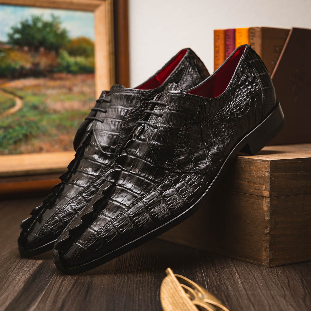 The Marco Di Milano Cancun Black features genuine hornback caiman crocodile shoes with a pointed toe, one upright and the other showing the branded brown leather sole—a striking choice in men's exotic footwear.
