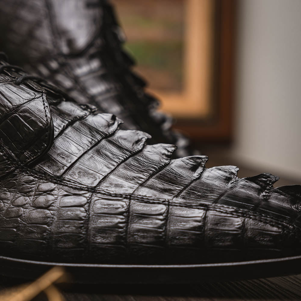The Marco Di Milano Cancun Black features genuine hornback caiman crocodile shoes with a pointed toe, one upright and the other showing the branded brown leather sole—a striking choice in men's exotic footwear.