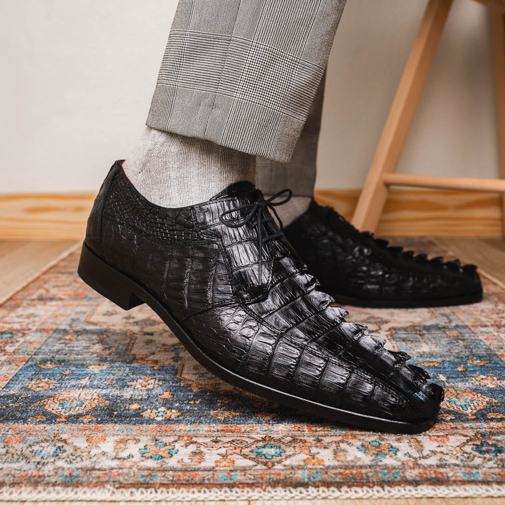 The Marco Di Milano Cancun Black features genuine hornback caiman crocodile shoes with a pointed toe, one upright and the other showing the branded brown leather sole—a striking choice in men's exotic footwear.